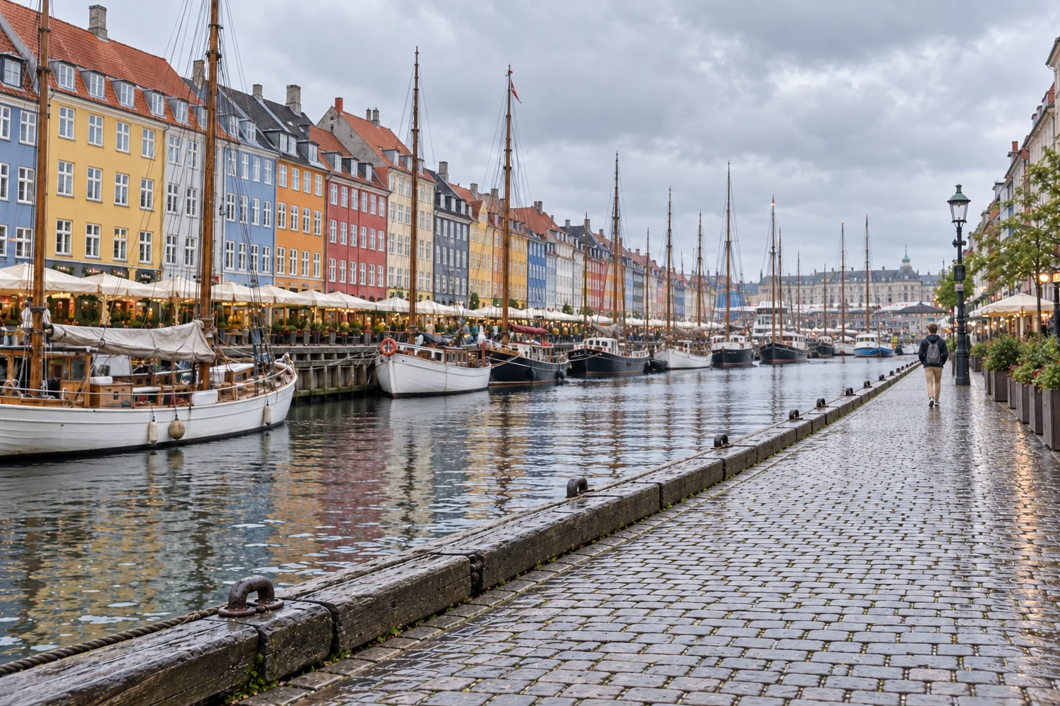Daan loopt klein langs de boten en gekleurde gevels van Nyhavn