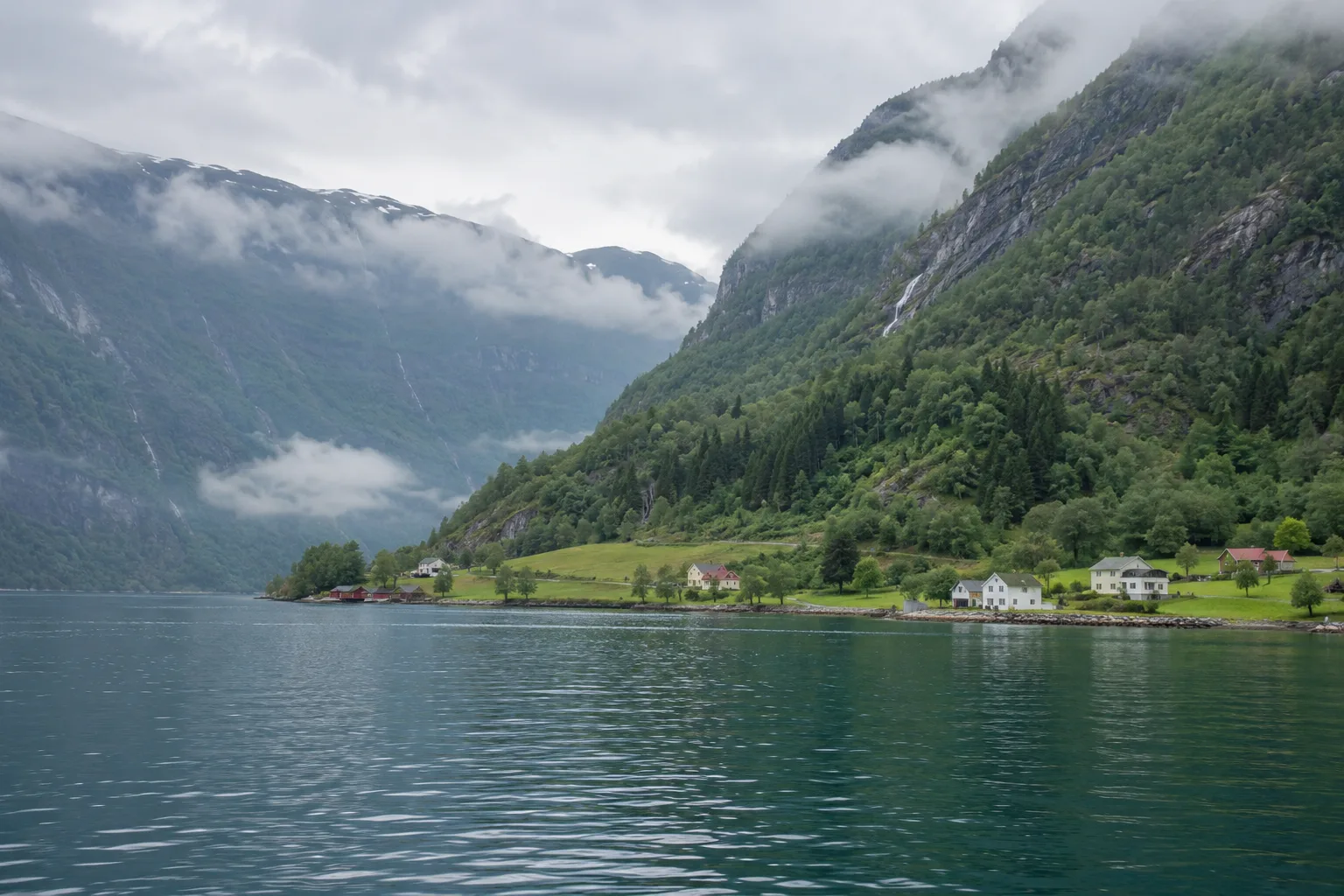 Berghellingen en huizen aan het Lustrafjord onder lage bewolking